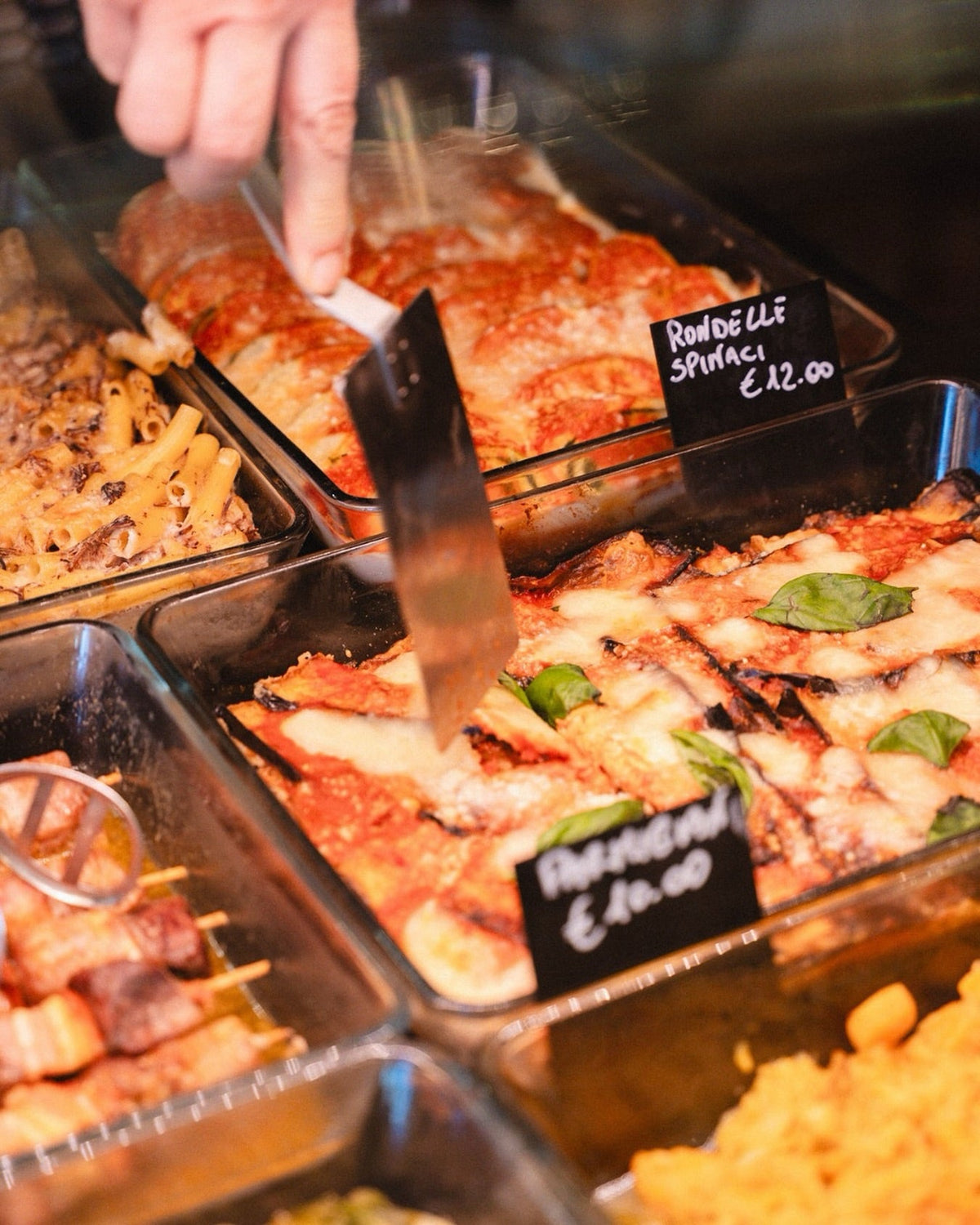 Spatola che serve piatti pronti dalla vetrina della gastronomia